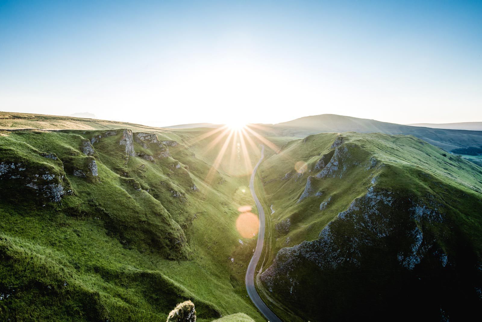 Shining sun behind green mountains